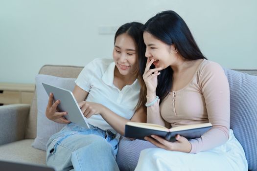 lgbtq, lgbt concept, homosexuality, portrait of two asian women posing happy together and loving each other while playing tablet at sofa.