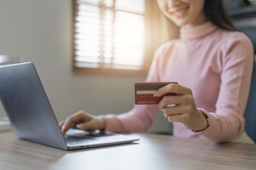 Young person using credit card and laptop computer. Online shopping, e-commerce concept.