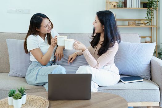 lgbtq, lgbt concept, homosexuality, portrait of two asian women posing happy together and loving each other while playing computer laptop on sofa.