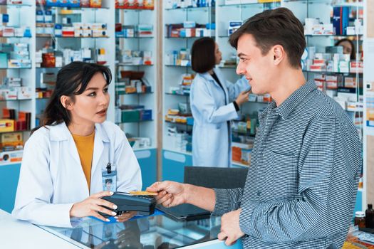 Payment by credit card with payment terminal in qualified drugstore. Modern financial payment of electric money. Caucasian customer purchase medication in pharmacy with prescription from pharmacist.