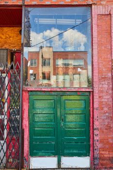 Image of Alley large double green doors with glass display above along red brick wall