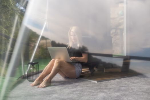 Happy young woman chatting online by using laptop in dome camping. Glamping vacation concept.