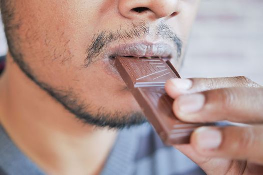 young man eating dark chocolate close up .