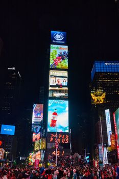 Image of Tourists surround Times Square in New York City at night with focus on advertisements