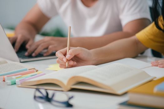 Young woman and man studying for a test or an exam. Tutor book with friends. Young students campus or classmates helps friend catching up workbook and learning tutoring in classroom, teaching, learning