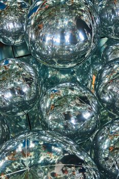 Image of Detail of dozens of reflective mirror helium balloons showing more spheres and tourists