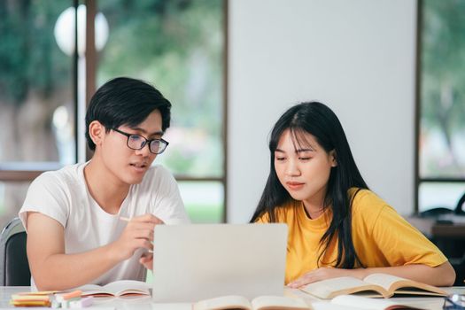 Young woman and man studying for a test or an exam. Tutor book with friends. Young students campus or classmates helps friend catching up workbook and learning tutoring in classroom, teaching, learning