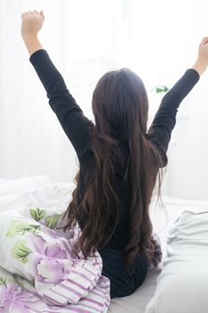 Cute teenage girl stretching on the bed in her room having fun