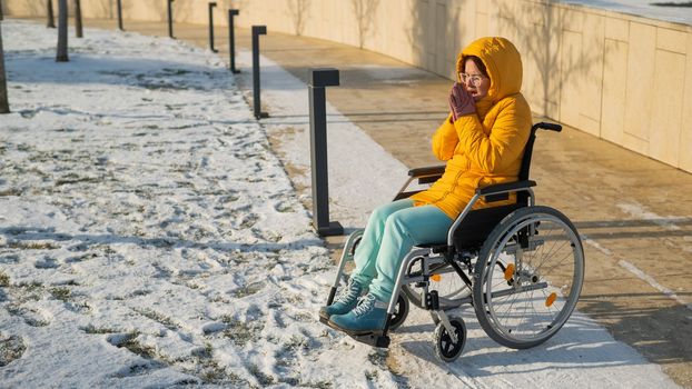 Woman in wheelchair getting cold in winter park
