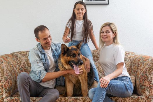 Mom, dad, and daughter having fun playing with big dog