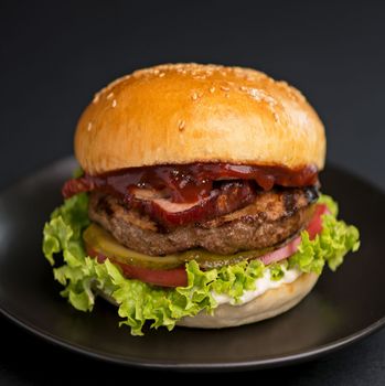 Big tasty burger with beef cutlet on a black background