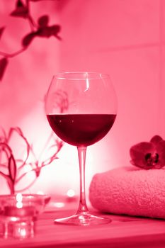 Spa-beauty salon, wellness center. Spa treatment aromatherapy for the female body in the bathroom with a glass of wine, with candles, oils and salt.Viva Magenta Background color
