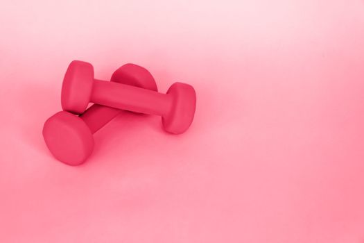 Green dumbbells for sports on a pink background. Sports, sports nutrition, healthy eating, diet. Space for the text. Viva Magenta Background color