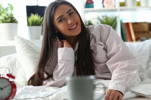 Smiling beautiful woman on bed in shirt. Positive mood and happy morning concept