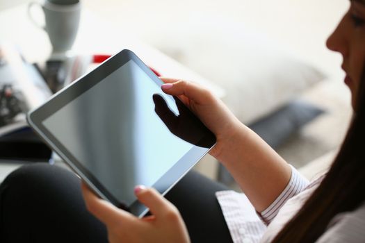 Female hands hold modern tablet at home. Mobile application developer or browsing information on the internet concept