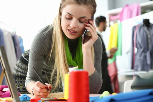 Woman designer stylist takes an order for tailoring by phone. Atelier services concept
