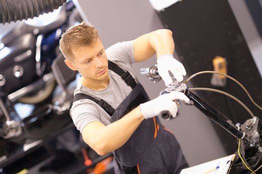 Auto mechanic repairs motorcycle fork in workshop. Motorcycle repair and maintenance concept