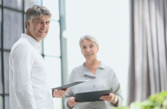 Professional business man and woman standing back to back in the office looking at the camer