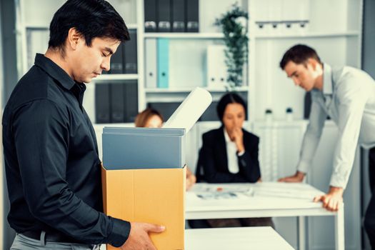 Depressed and disappointed employee packing his belongings after being fired for not being competent. Gossiped by his colleagues behind his back. Layoff due to economic depression.