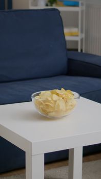 Modern empty apartament with nobody in it is ready for night party having chips bowl on woden table. Living room is prepared for friends gathering celebrating wekeend birthday party late at night