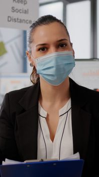 Business woman with face mask during online web internet videocall with remote team. Freelancer having communication meeting in new normal office on video call conference zoom meeting during pandemic