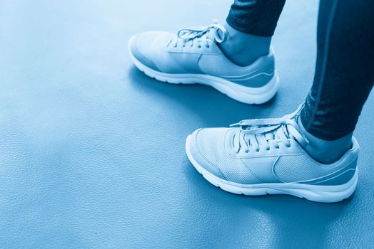 Close up front view of woman's hands tying shoelaces on sneakers in the gym.