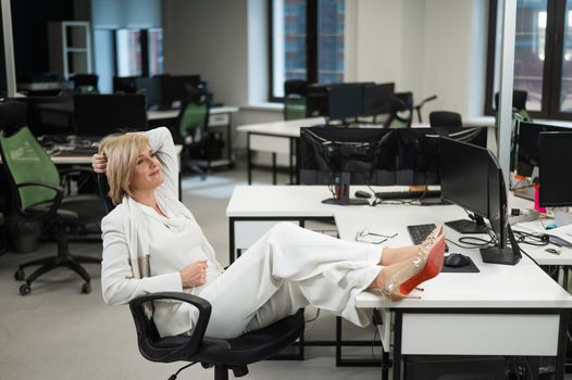 Caucasian woman sitting with her legs folded on the desk in the office
