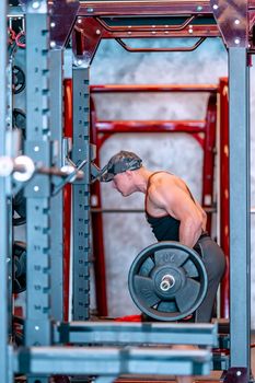 young athlete lifts barbell in gym. 