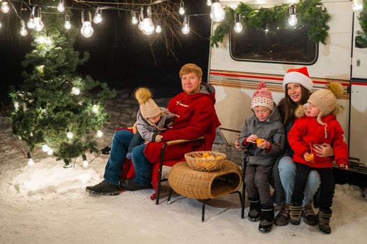 Happy Caucasian family celebrating Christmas outdoors. Parents and three sons travel in a camper