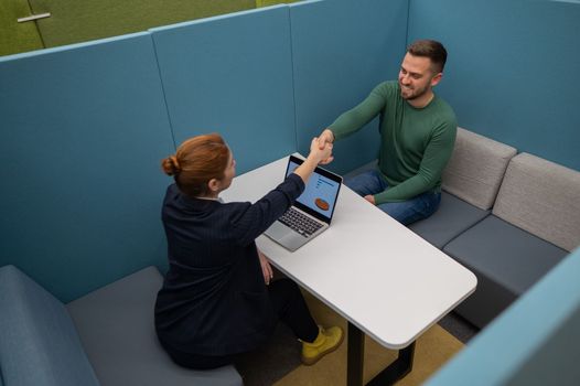 Caucasian woman and bearded man at the talks in the room. Handshake for a job interview