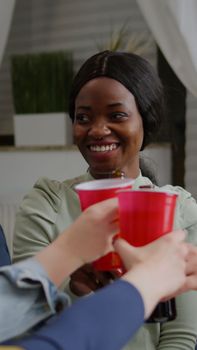 Mixed race friends socializing while sharing socia media advice relaxing on sofa late at night in living room. Multi-ethnic people hanging out, drinking beer enjoying time together during fun party.