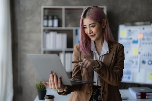 Asian Business woman working to analyze technical price graph and indicator with business team talking by cell phone. account or saving money or insurance concept.