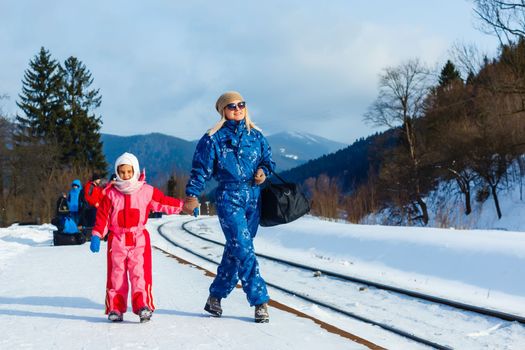 mother and daughter are wearing ski suits near the railway