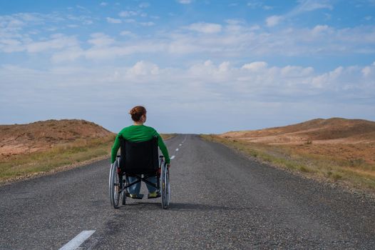 Woman in a wheelchair on a highway in the steppes