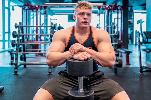 athlete resting in the gym between barbell exercises. 