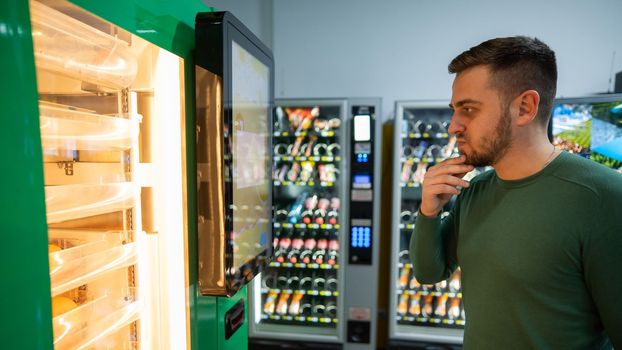 Caucasian man buys freshly squeezed orange juice from vending machine