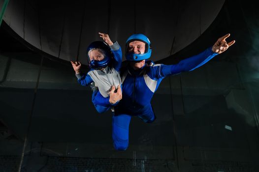 A man teaches a boy to fly in a wind tunnel. Lack of gravity