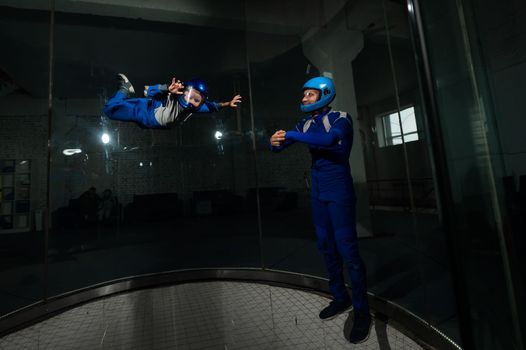 A man teaches a boy to fly in a wind tunnel. Lack of gravity