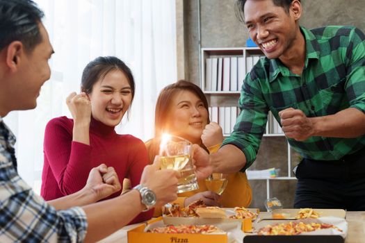 Friends at birthday party clinking glasses with champagne and pizza, enjoying Christmas vacation, pizza on the table. Holiday Party event