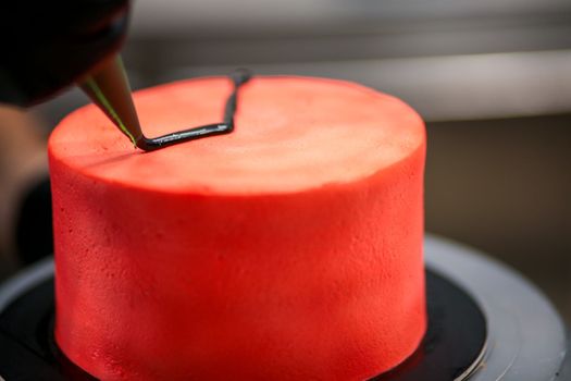topping a red cake with black dark chocolate icing