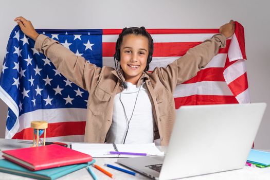 Little boy cheering with American flag. Education online on laptop computer. Pupil in class.