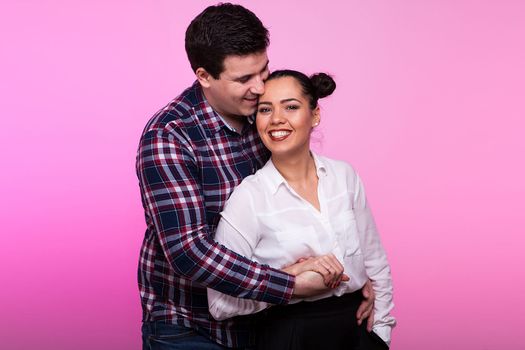 Man embracing a woman on pink background in studio photo