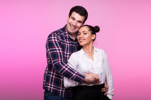 Husband embracing wife on pink background in studio photo