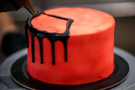 topping a red cake with black dark chocolate icing