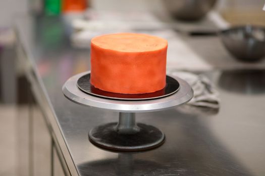 cook preparing a red frosted cake using air bush