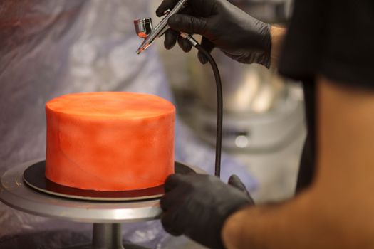 cook preparing a red frosted cake using air bush