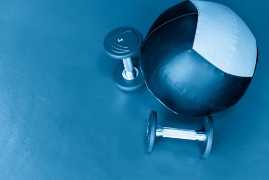 Close up shot of a medicine ball and two lifting dumbbells