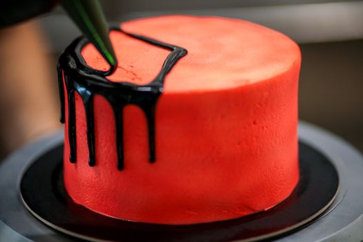 topping a red cake with black dark chocolate icing
