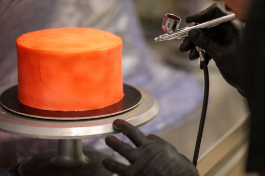 cook preparing a red frosted cake using air bush