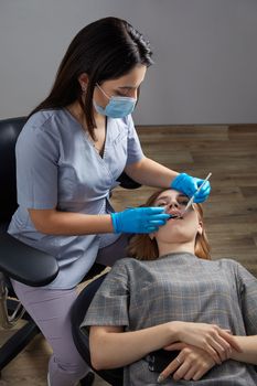 Dentist checking teeth of a patient with dental mirror. Woman having teeth examined at dentists